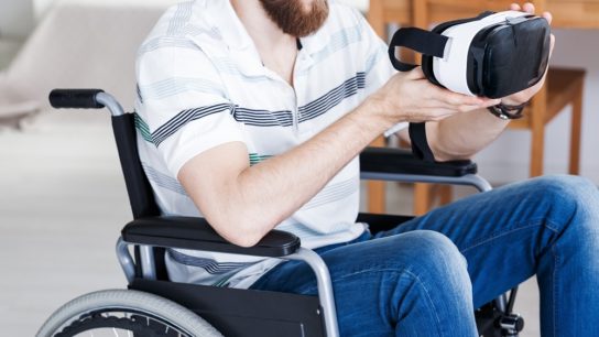 Man in a wheelchair holding virtual reality goggles