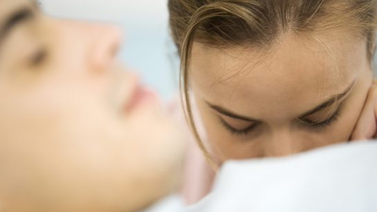 man sleeping and woman has forehead down on him