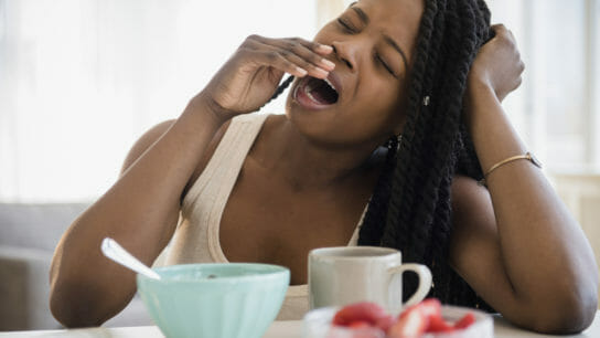 Black woman yawning at table
